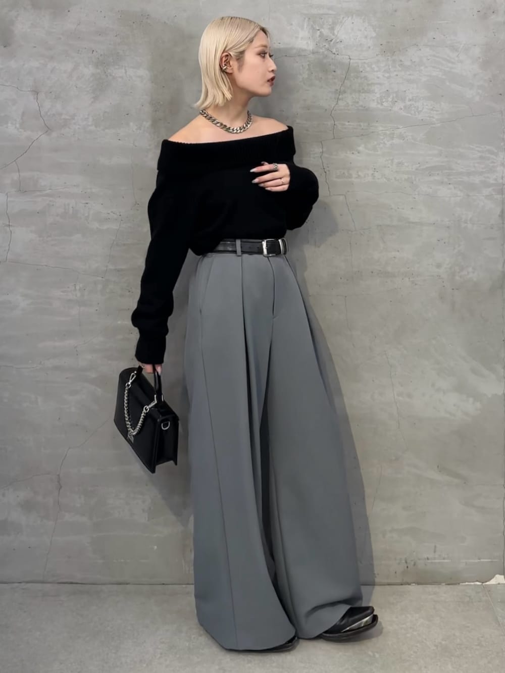 ブラック系のニット/セーター、ブラック系のショルダーバッグ、グレー系のスラックスを着用したレディースの冬コーディネートの3枚目の写真