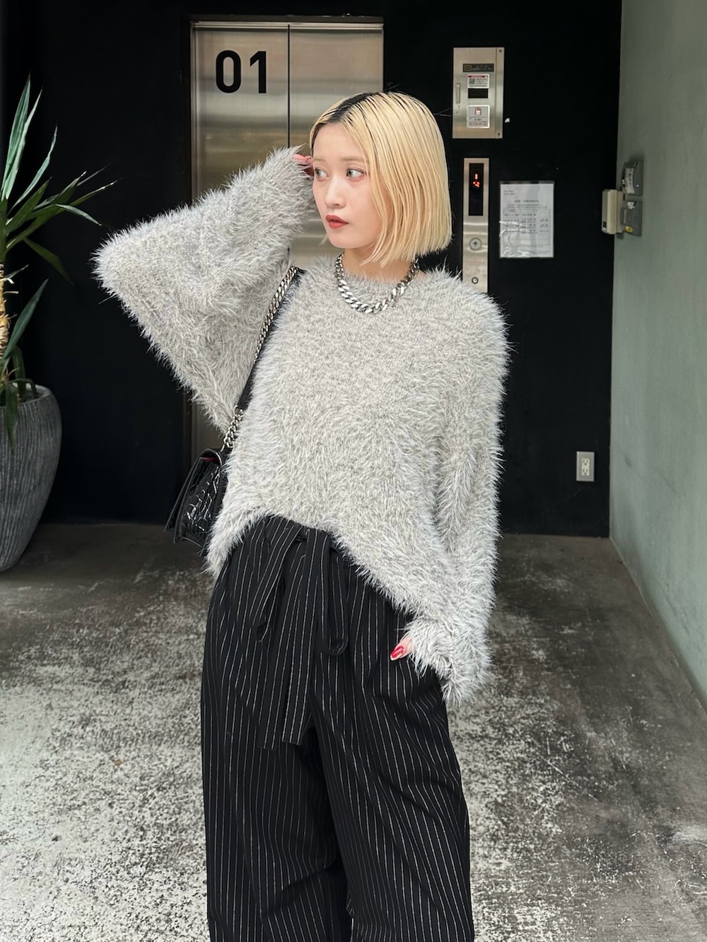 グレー系のニット/セーター、ブラック系のその他パンツ、シルバー系のネックレスを着用したレディースの秋コーディネートの5枚目の写真