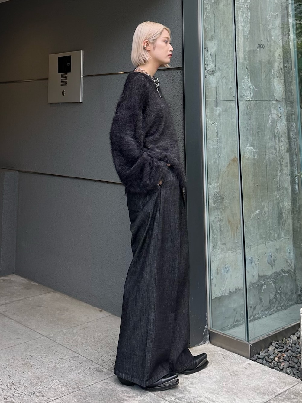 ブラック系のニット/セーター、ブラック系のデニムパンツ、シルバー系のネックレスを着用したレディースの秋コーディネートの3枚目の写真