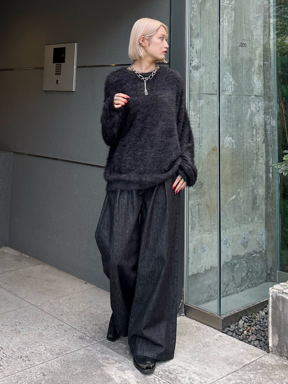 ブラック系のニット/セーター、ブラック系のデニムパンツ、シルバー系のネックレスを着用したレディースの秋コーディネートの2枚目の写真