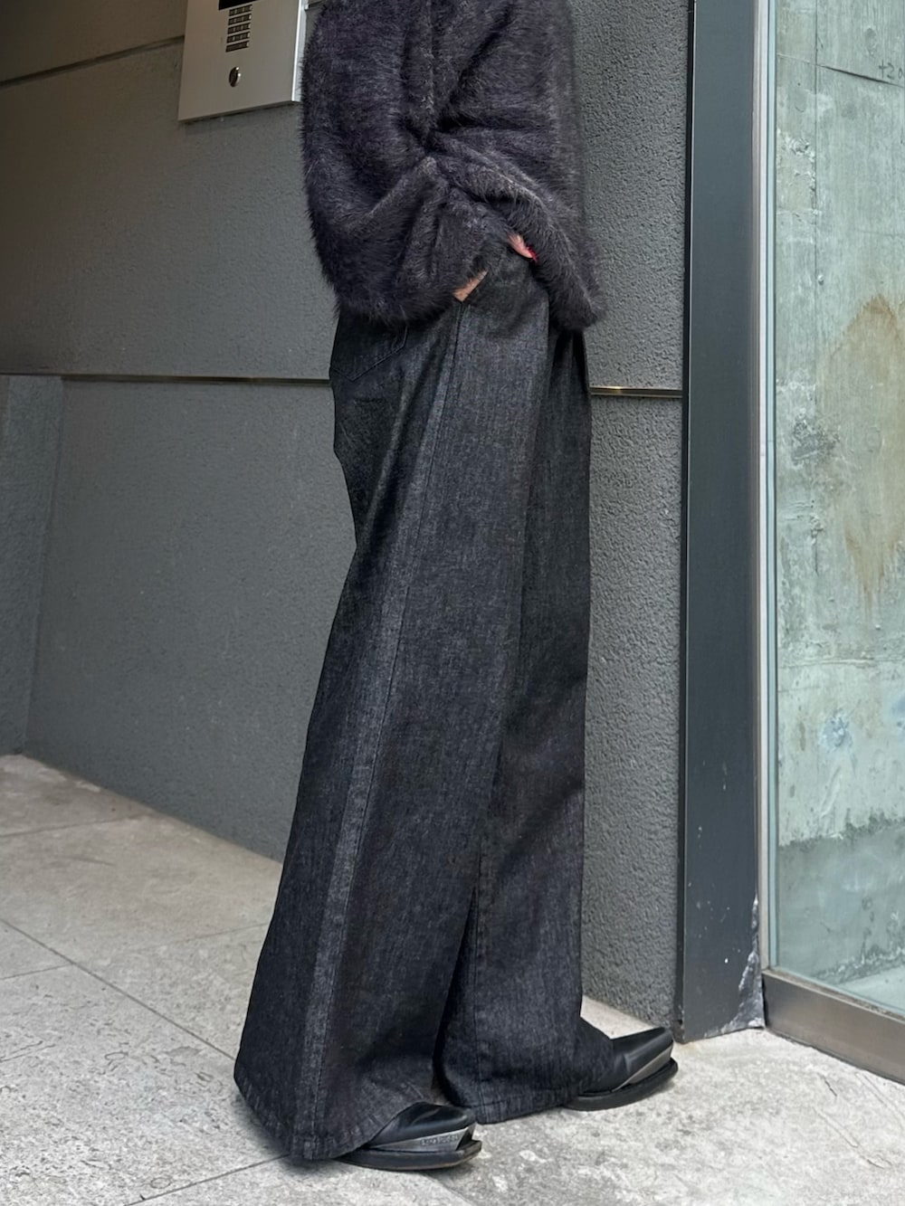 ブラック系のニット/セーター、ブラック系のデニムパンツ、シルバー系のネックレスを着用したレディースの秋コーディネートの8枚目の写真