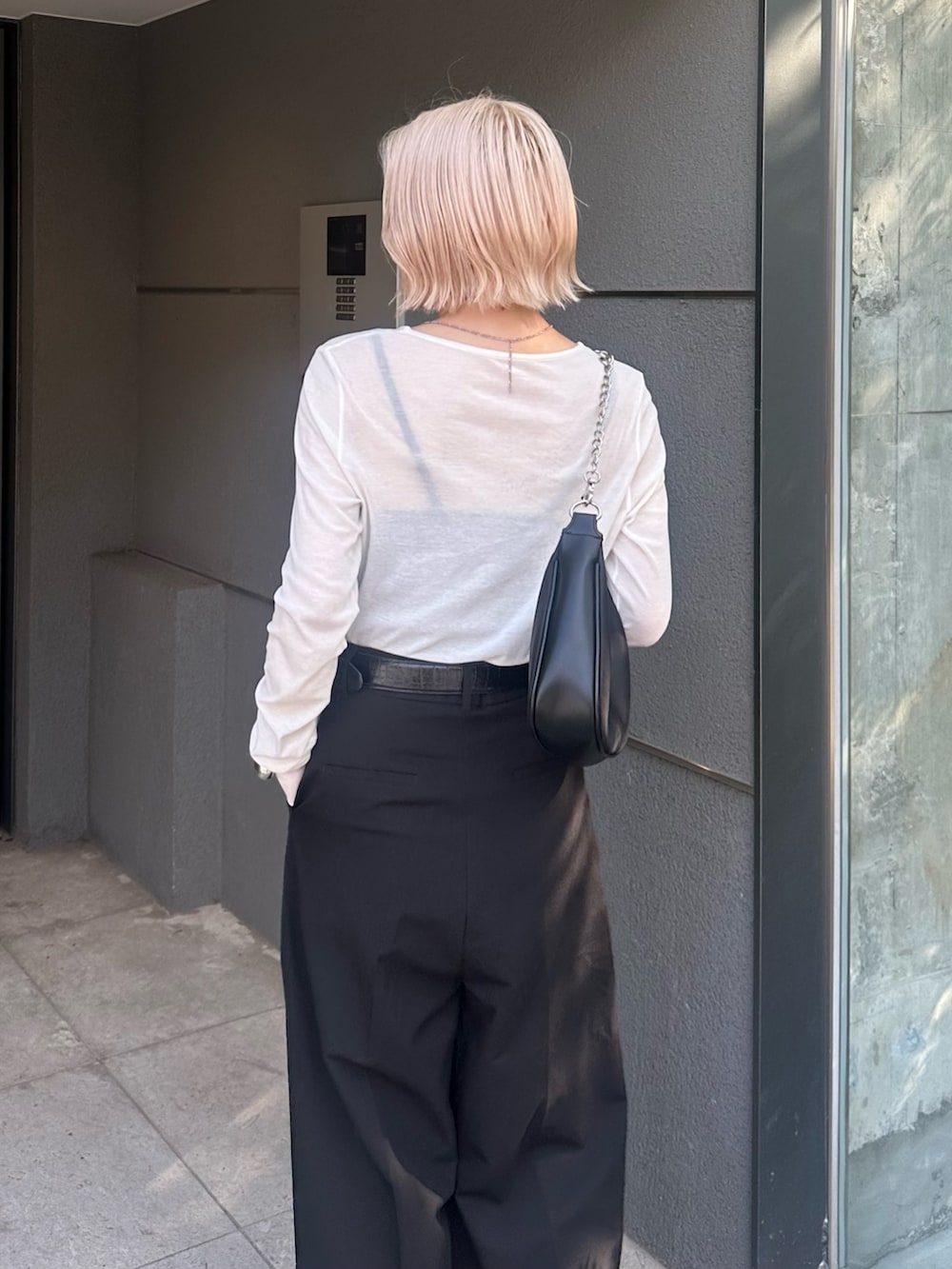 ブラック系のスラックス、ブラック系のショルダーバッグ、ホワイト系のTシャツ/カットソーを着用したレディースの夏コーディネートの7枚目の写真