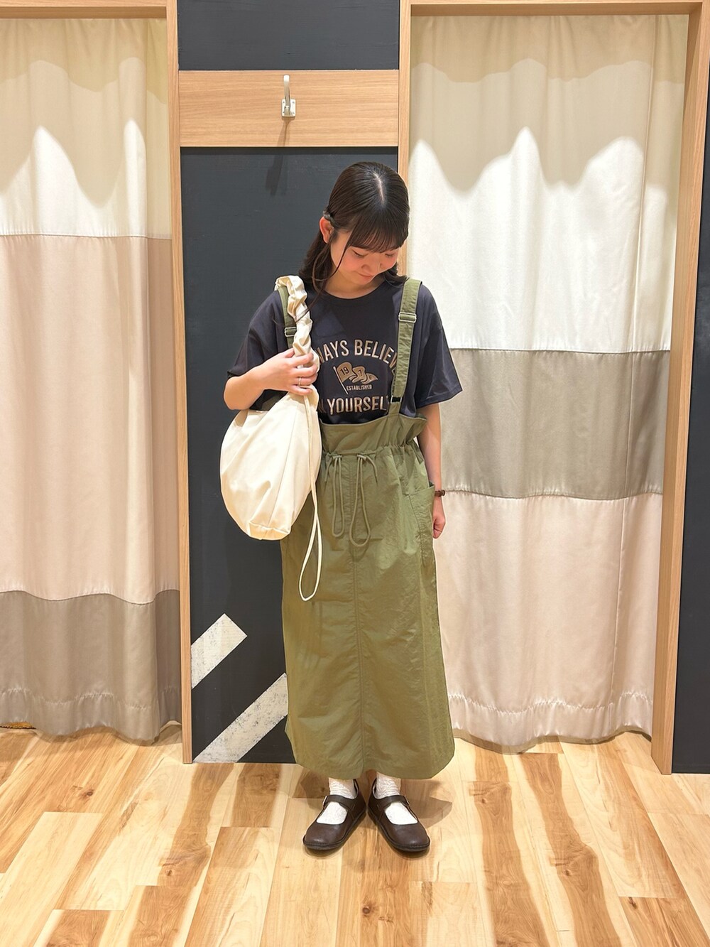 グレー系のTシャツ/カットソー、グリーン系のスカート、ホワイト系のハンドバッグを着用したレディースの春コーディネートの2枚目の写真