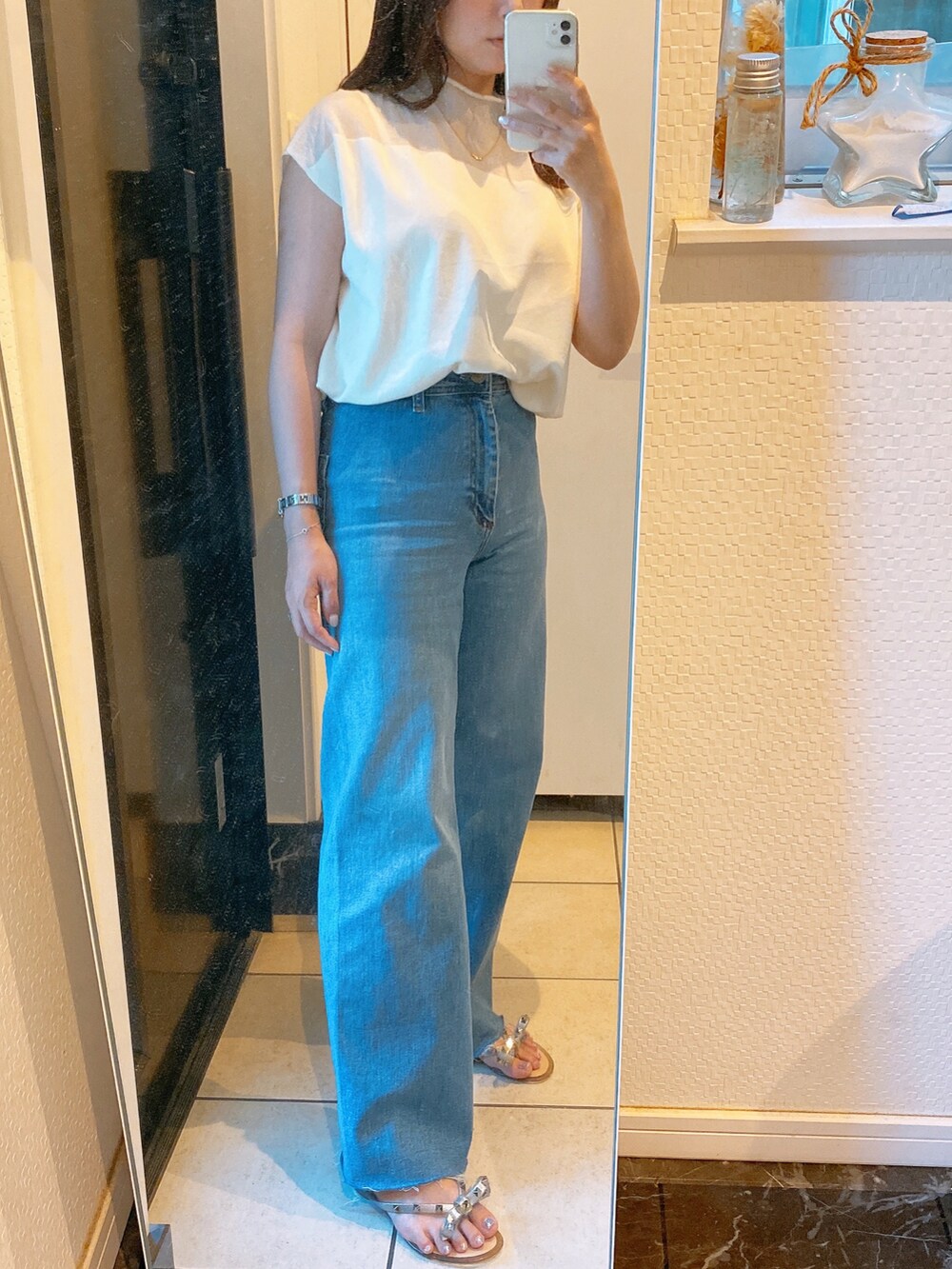 ホワイト系のトップス、ブルー系のパンツ、シルバー系のサンダルを着用したレディースの夏コーディネートの2枚目の写真