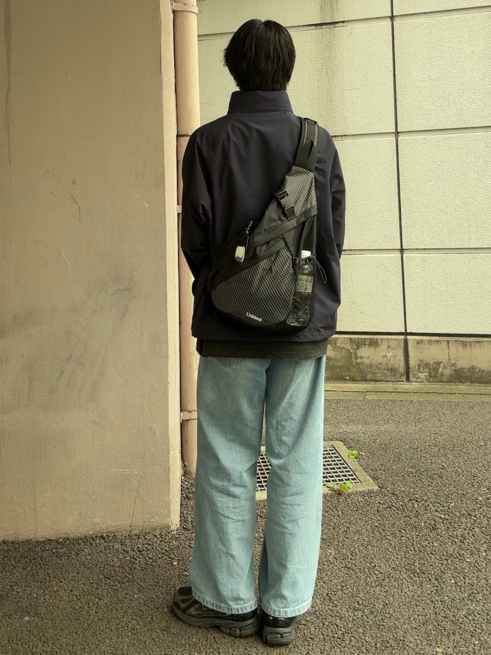ブルー系のナイロンジャケット、ブラック系のボディバッグ/ウエストポーチ、ブルー系のデニムパンツを着用したメンズの秋コーディネートの2枚目の写真