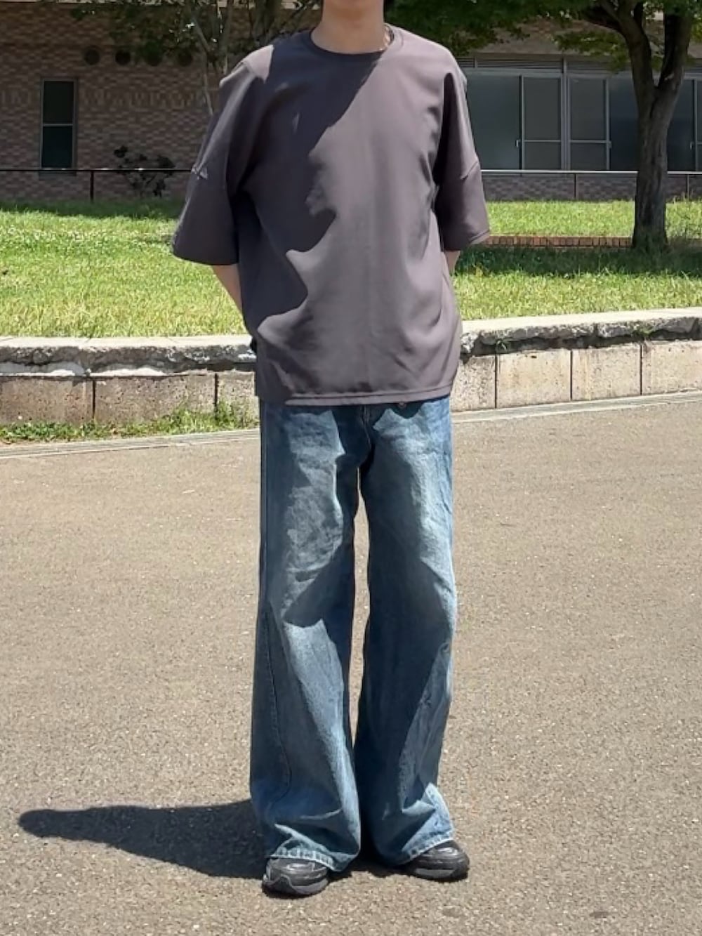 グレー系のTシャツ/カットソー、ブラック系のスニーカー、ブルー系のデニムパンツを着用したメンズの夏コーディネートの2枚目の写真