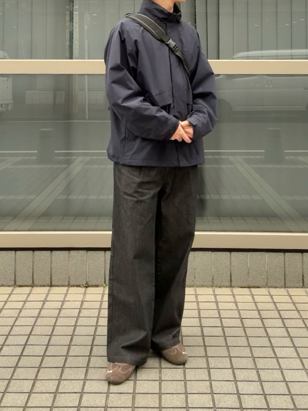 ブルー系のナイロンジャケット、ブラック系のデニムパンツ、ブラウン系のスニーカーを着用したメンズの春コーディネートの3枚目の写真