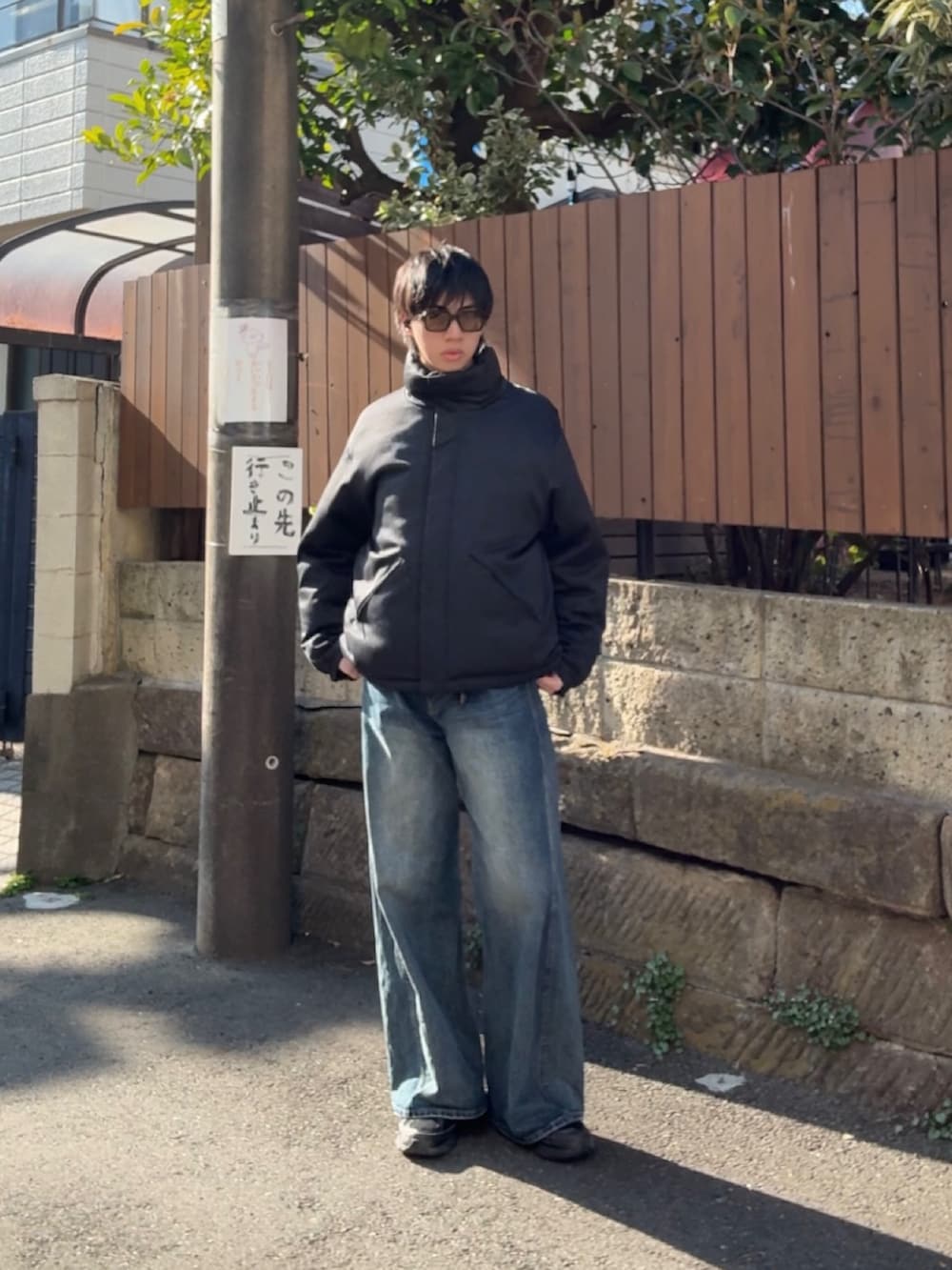 グレー系のダウンジャケット/コート、ブルー系のデニムパンツ、ブラック系のスニーカーを着用したメンズの春コーディネートの3枚目の写真