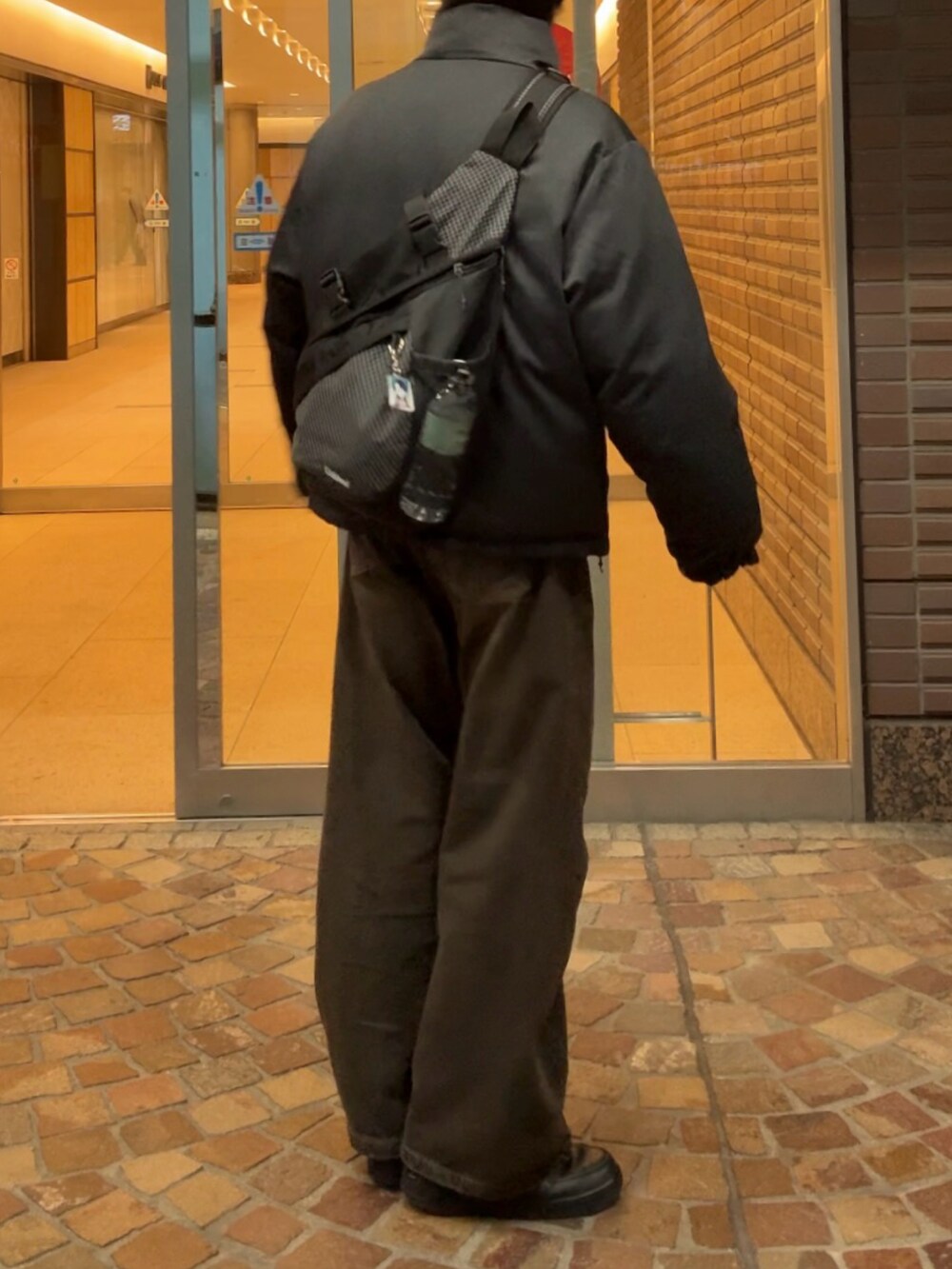 グレー系のダウンジャケット/コート、ブラック系のデニムパンツ、ブラック系のスニーカーを着用したメンズの冬コーディネートの2枚目の写真