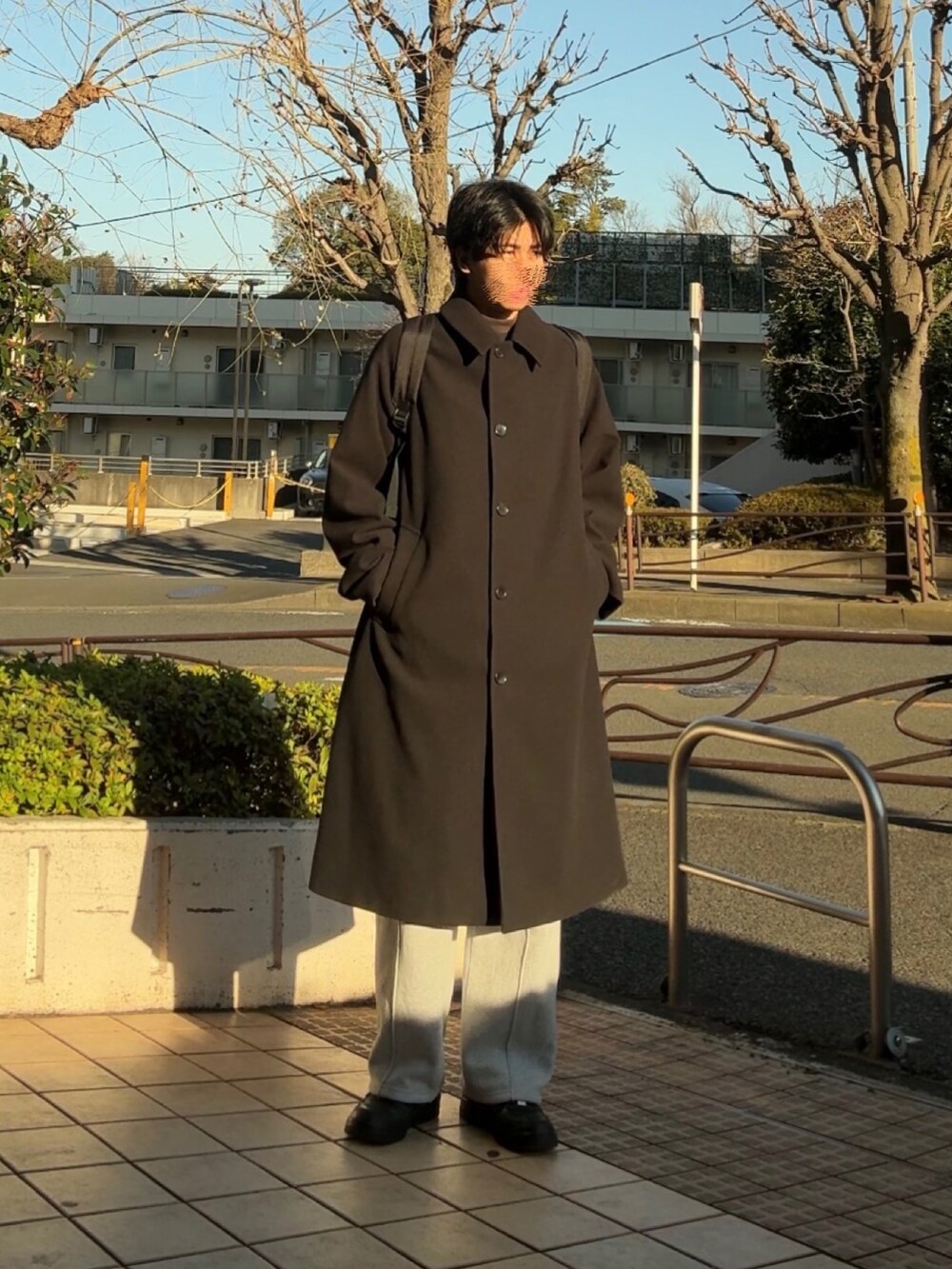 ブラック系のステンカラーコート、グレー系のスウェットパンツ、ブラック系のスニーカーを着用したメンズの冬コーディネートの2枚目の写真