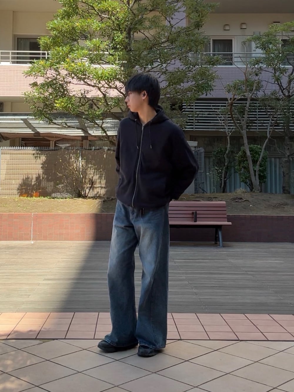 ブルー系のデニムパンツ、ブラック系のスニーカー、ブラック系のパーカーを着用したメンズの春コーディネートの2枚目の写真