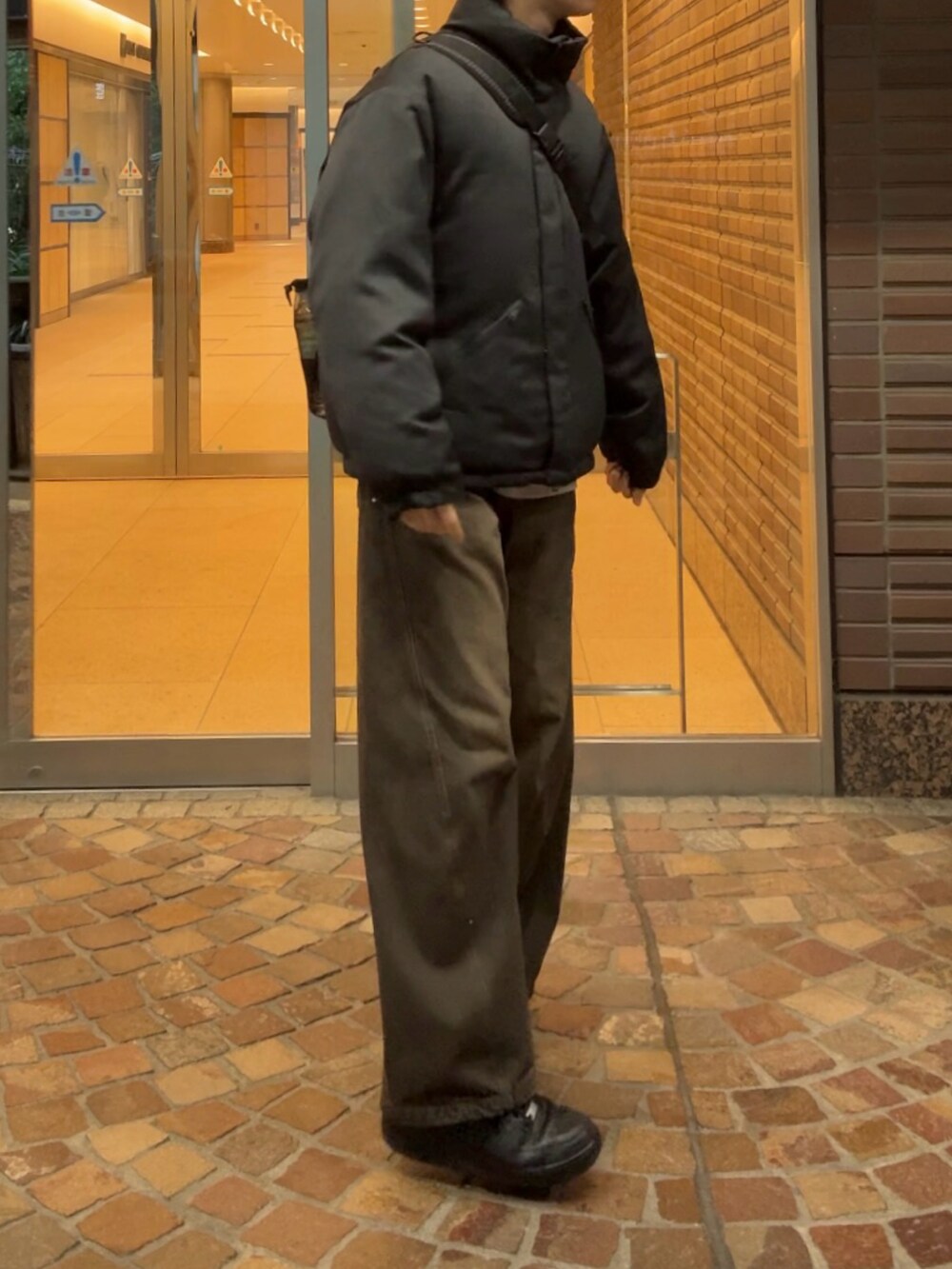 グレー系のダウンジャケット/コート、ブラック系のデニムパンツ、ブラック系のスニーカーを着用したメンズの冬コーディネートの3枚目の写真