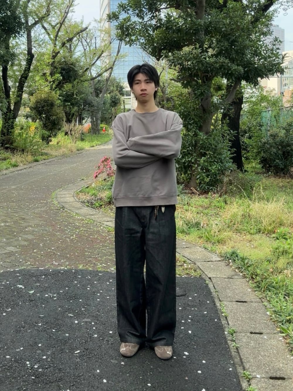 ブラック系のデニムパンツ、ブラウン系のスニーカー、グレー系のスウェットを着用したメンズの春コーディネートの2枚目の写真