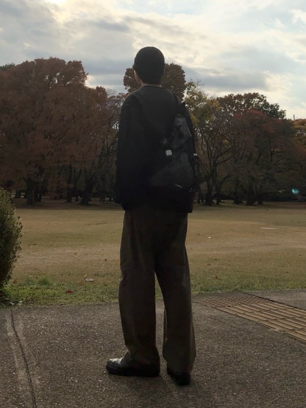 ブラック系のスニーカー、グリーン系のチノパンツ、ベージュ系のスウェットを着用したメンズの秋コーディネートの3枚目の写真