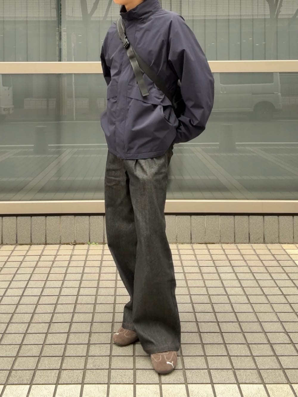 ブルー系のナイロンジャケット、ブラック系のデニムパンツ、ブラウン系のスニーカーを着用したメンズの春コーディネートの2枚目の写真