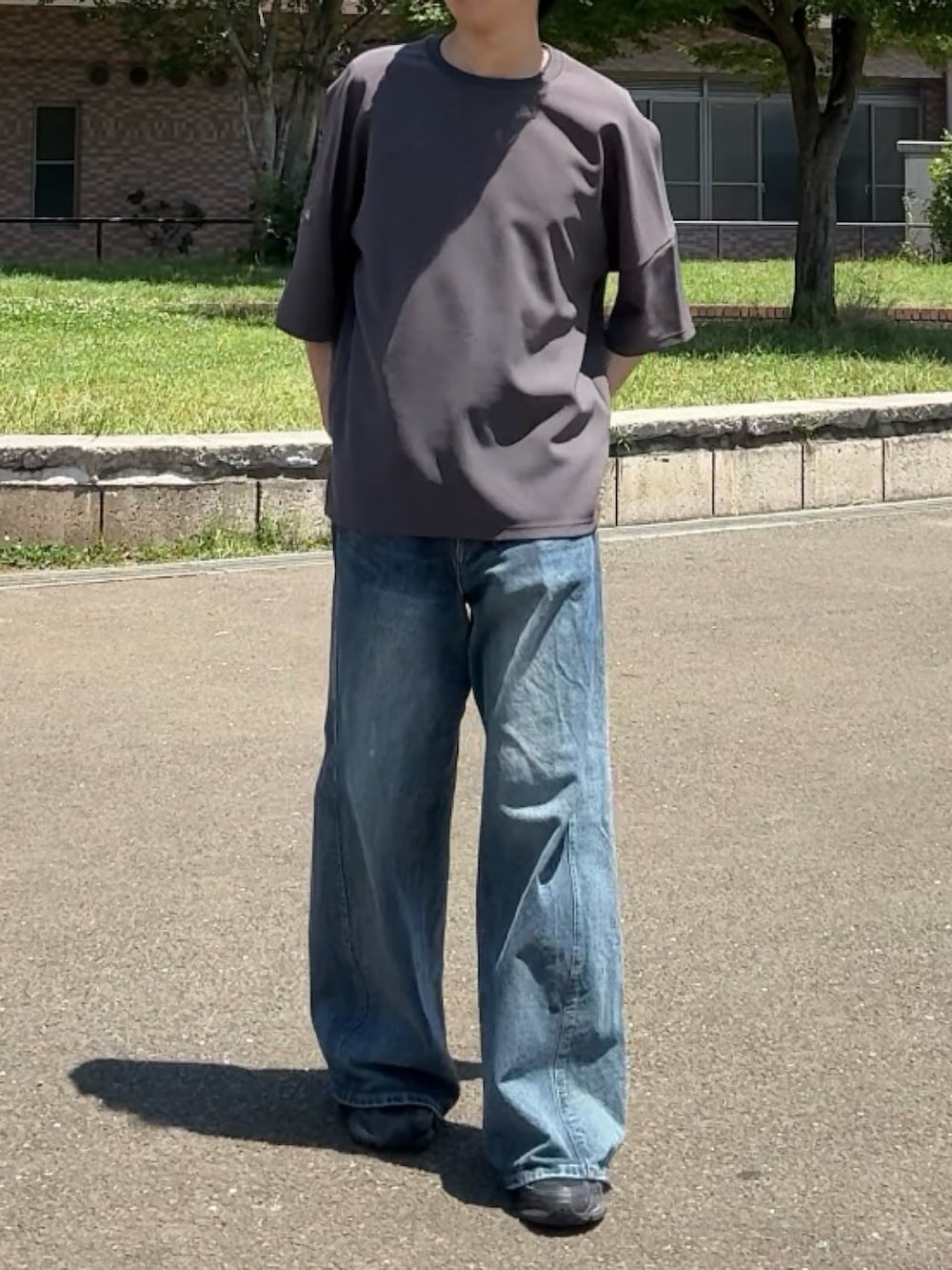 グレー系のTシャツ/カットソー、ブラック系のスニーカー、ブルー系のデニムパンツを着用したメンズの夏コーディネートの3枚目の写真
