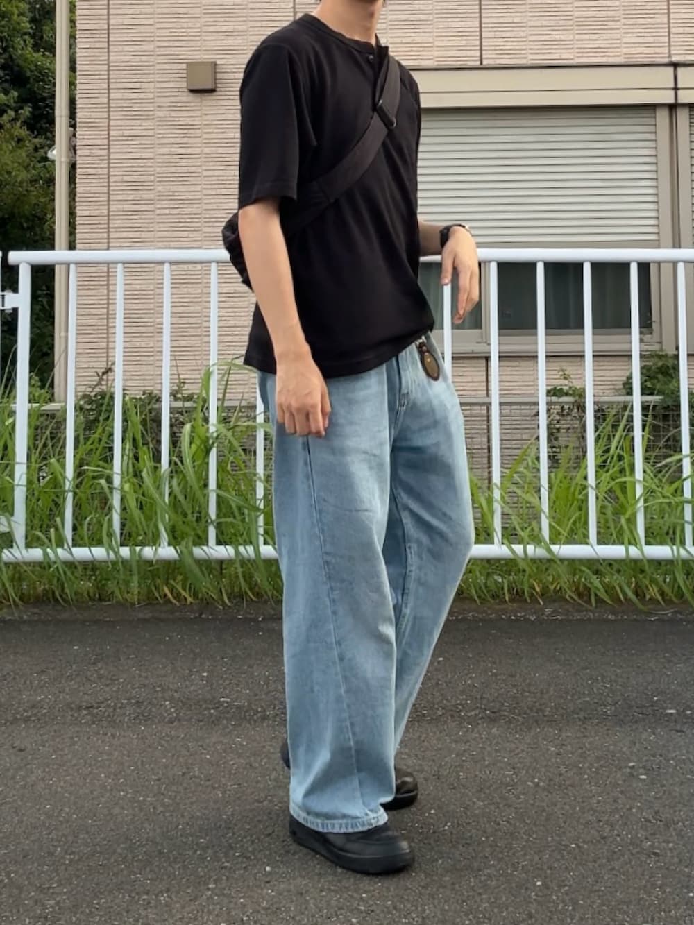 ブルー系のデニムパンツ、ブラック系のTシャツ/カットソー、ブラック系のスニーカーを着用したメンズの夏コーディネートの2枚目の写真