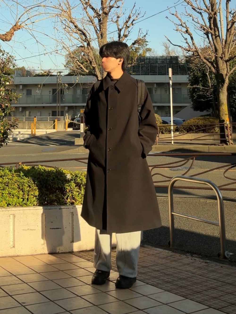 ブラック系のステンカラーコート、グレー系のスウェットパンツ、ブラック系のスニーカーを着用したメンズの冬コーディネートの3枚目の写真