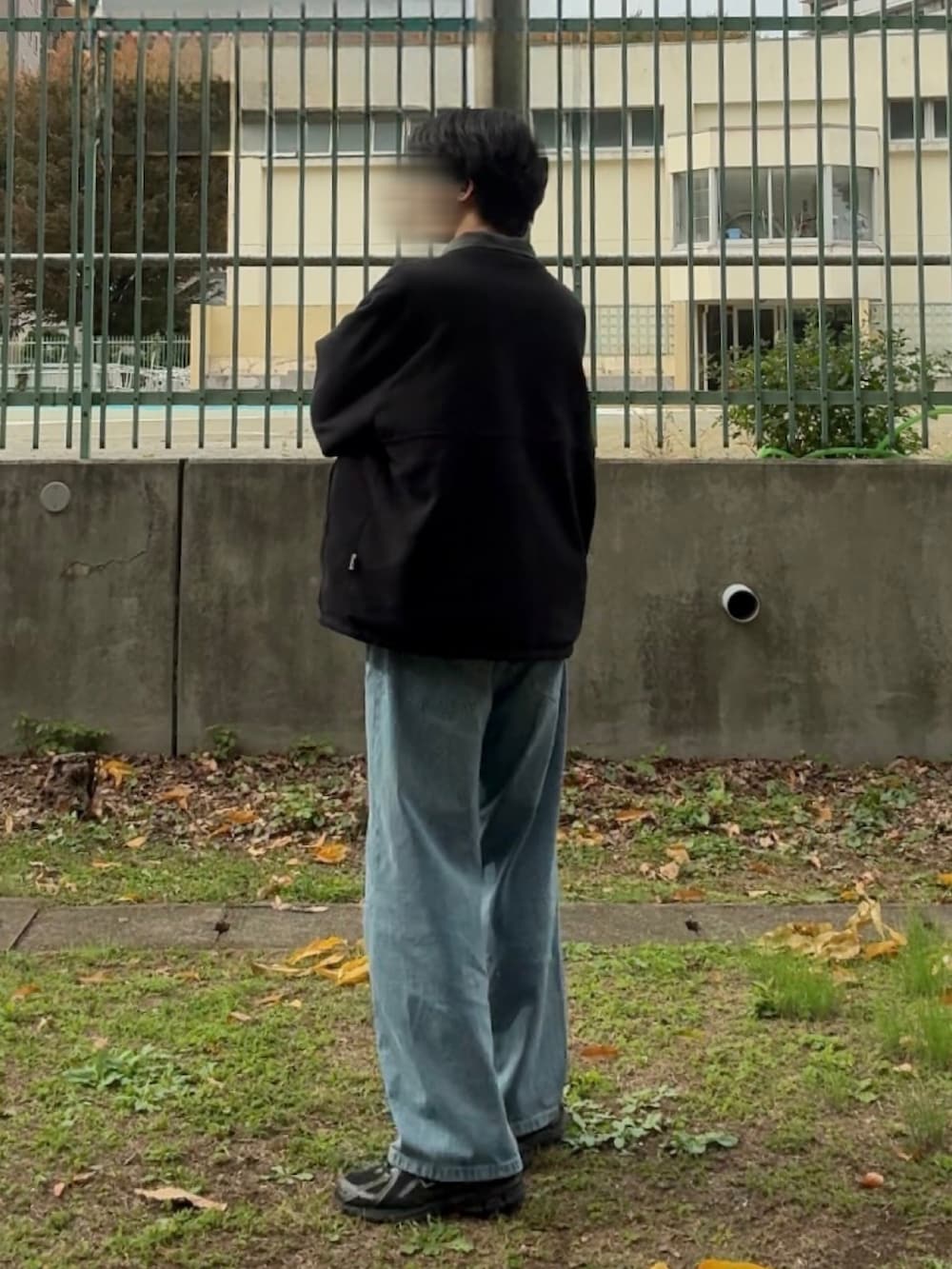 グリーン系のブルゾン、ブルー系のデニムパンツ、ブラック系のスニーカーを着用したメンズの秋コーディネートの2枚目の写真