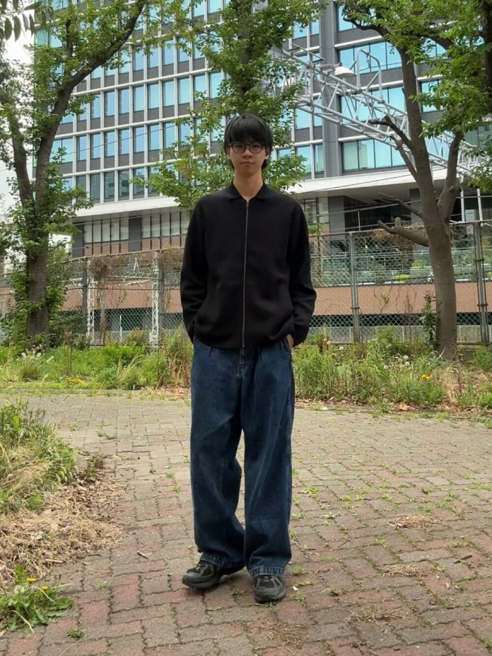 ブラック系のカーディガン/ボレロ、ブルー系のデニムパンツ、ブラック系のスニーカーを着用したメンズの春コーディネートの2枚目の写真