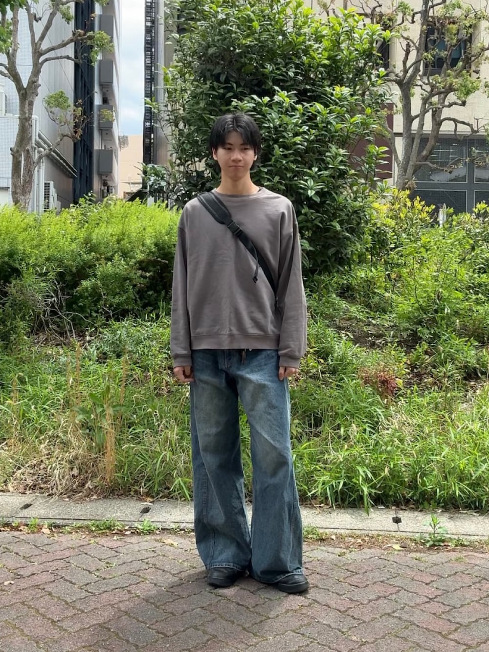 グレー系のスウェット、ブルー系のデニムパンツ、ブラック系のボディバッグ/ウエストポーチを着用したメンズの春コーディネートの2枚目の写真