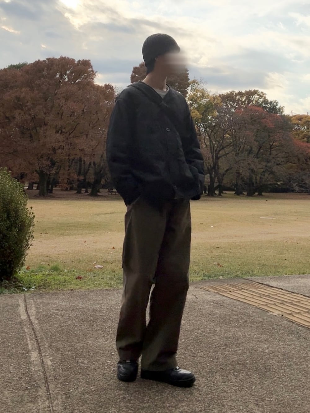 ブラック系のスニーカー、グリーン系のチノパンツ、ベージュ系のスウェットを着用したメンズの秋コーディネートの2枚目の写真