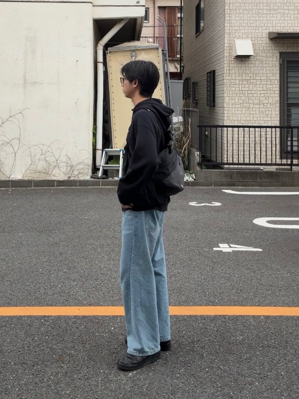 ブラック系のパーカー、ブルー系のデニムパンツ、ブラック系のスニーカーを着用したメンズの春コーディネートの2枚目の写真