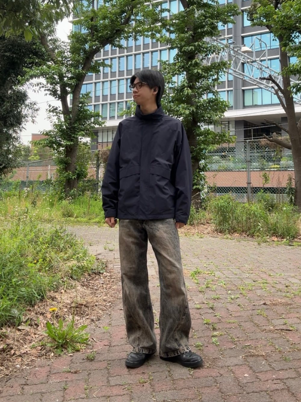ブルー系のナイロンジャケット、ブルー系のデニムパンツ、ブラック系のスニーカーを着用したメンズの春コーディネートの2枚目の写真