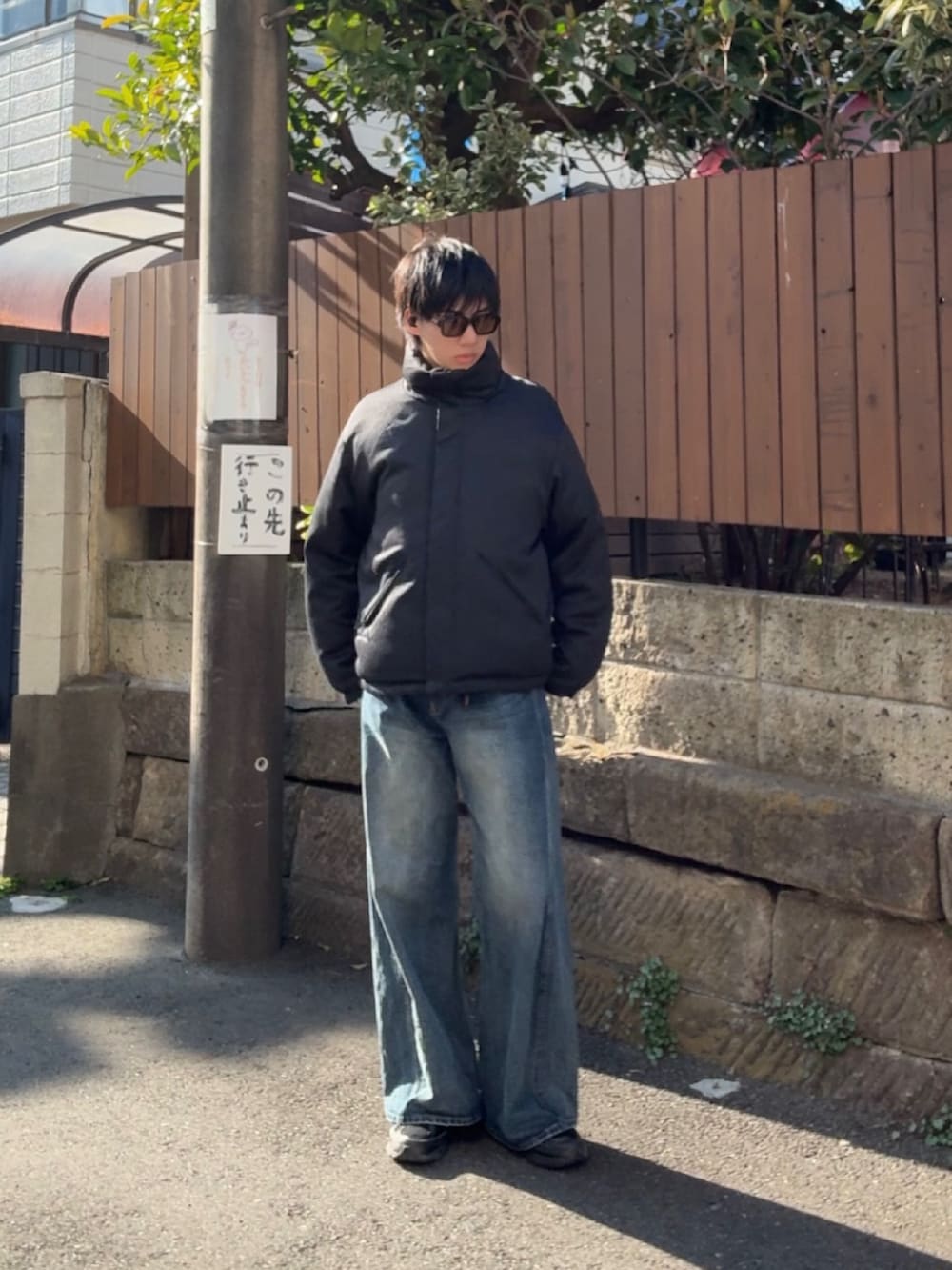 グレー系のダウンジャケット/コート、ブルー系のデニムパンツ、ブラック系のスニーカーを着用したメンズの春コーディネートの2枚目の写真