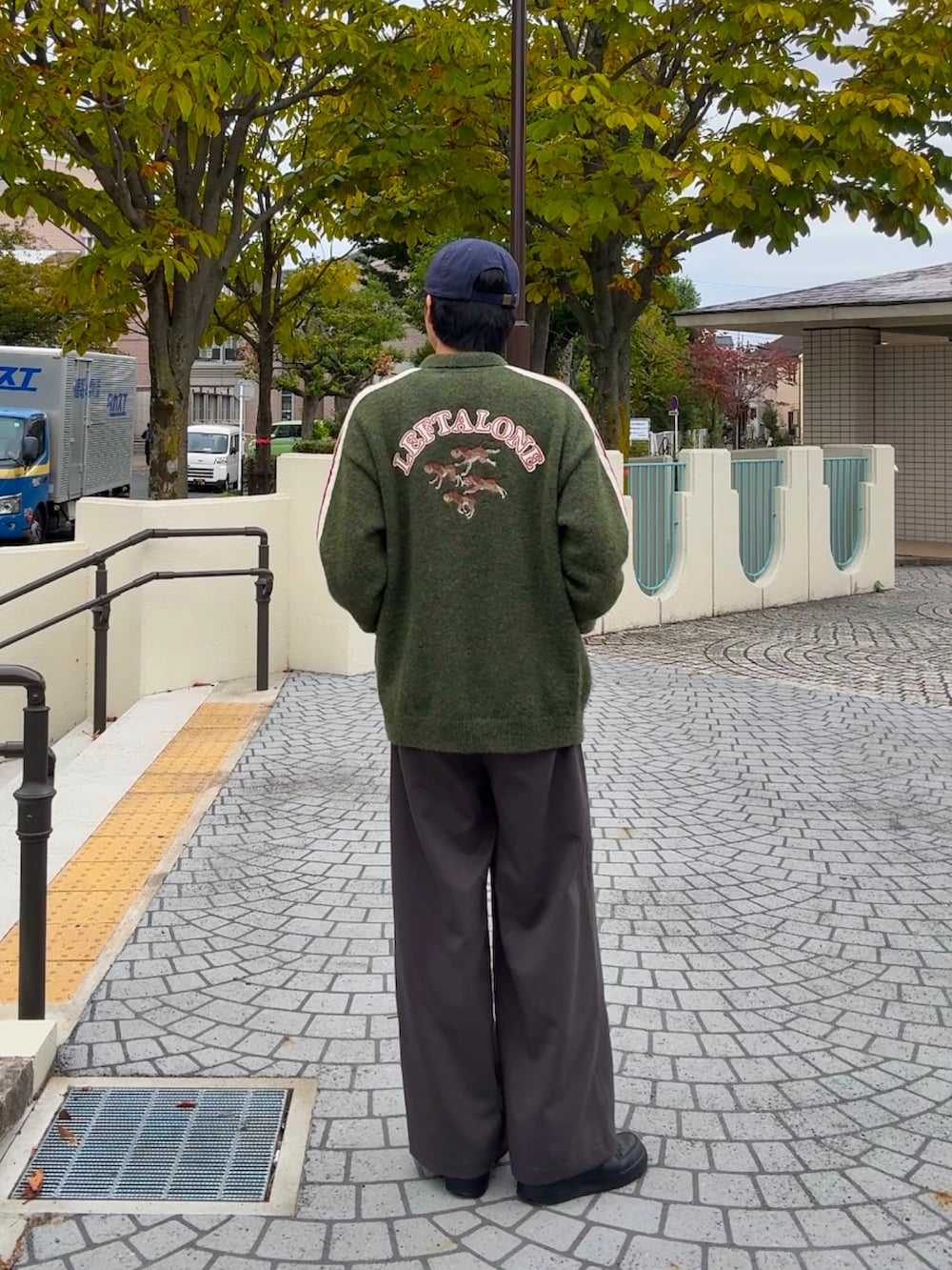 グリーン系のカーディガン/ボレロ、グレー系のスラックス、ブラック系のスニーカーを着用したメンズの秋コーディネートの2枚目の写真