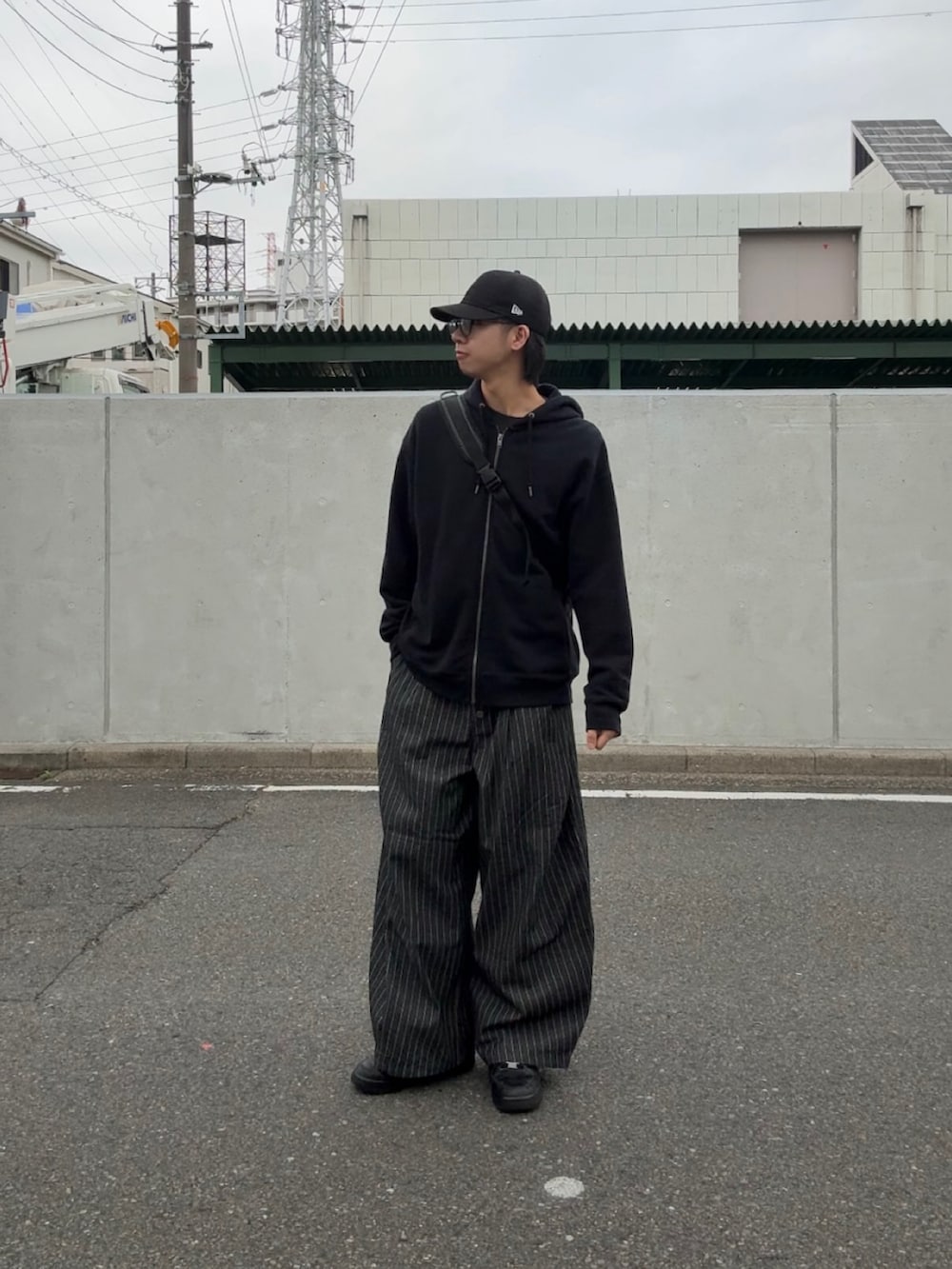 ブラック系のデニムパンツ、ブラック系のスニーカー、ブラック系のパーカーを着用したメンズの春コーディネートの2枚目の写真