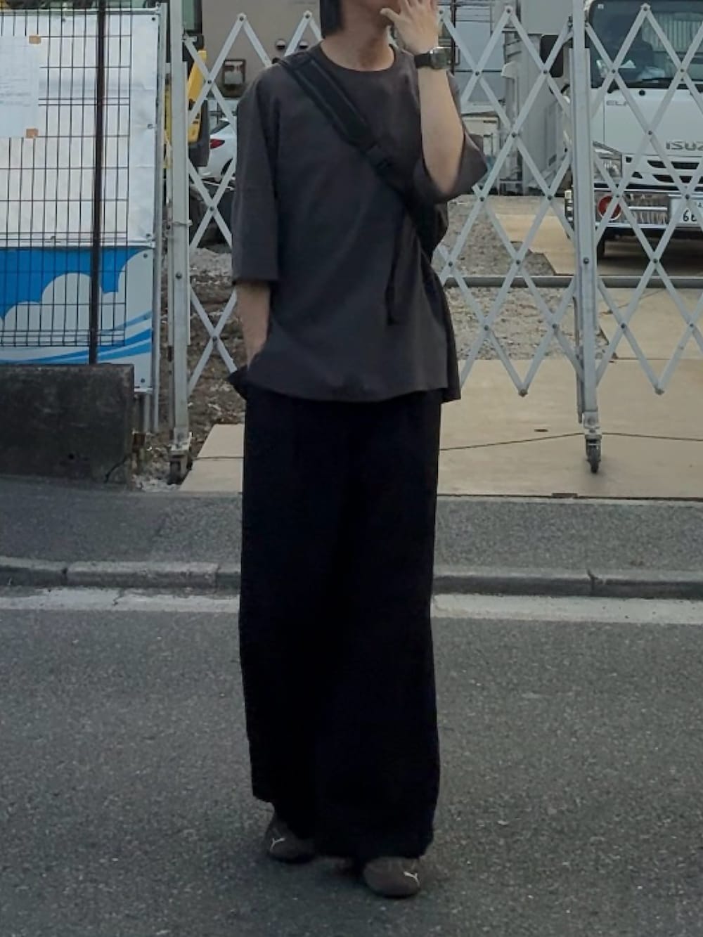 ブラック系のスラックス、グレー系のTシャツ/カットソー、ブラウン系のスニーカーを着用したメンズの春コーディネートの2枚目の写真
