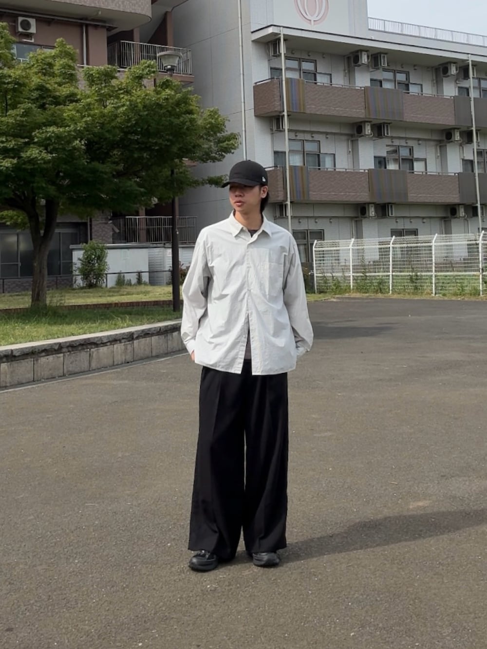 ホワイト系のシャツ/ブラウス、ブラック系のスニーカー、ブラック系のスラックスを着用したメンズの春コーディネートの2枚目の写真