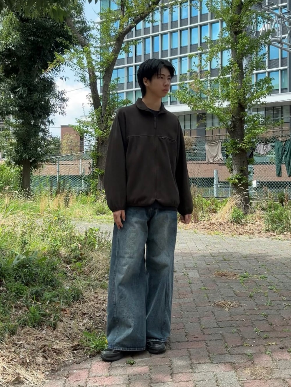 ブルー系のデニムパンツ、ブラック系のスニーカー、ブラウン系のブルゾンを着用したメンズの春コーディネートの2枚目の写真