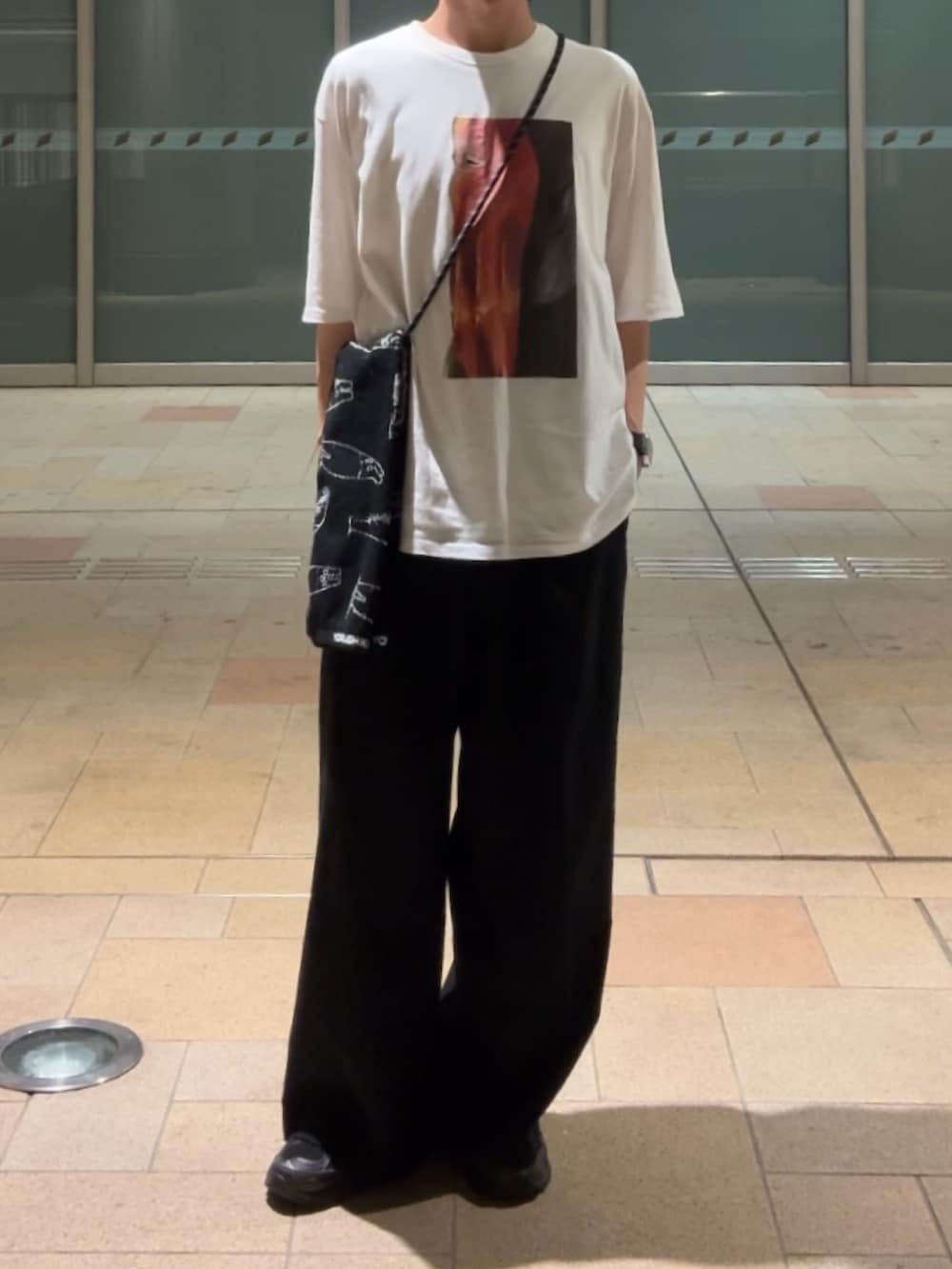 ブラック系のスラックス、ホワイト系のTシャツ/カットソー、ブラック系のスニーカーを着用したメンズの夏コーディネートの2枚目の写真