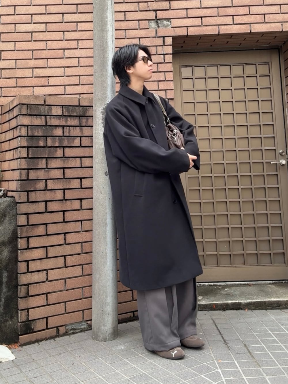 ブラック系のステンカラーコート、グレー系のスラックス、ブラウン系のスニーカーを着用したメンズの春コーディネートの3枚目の写真
