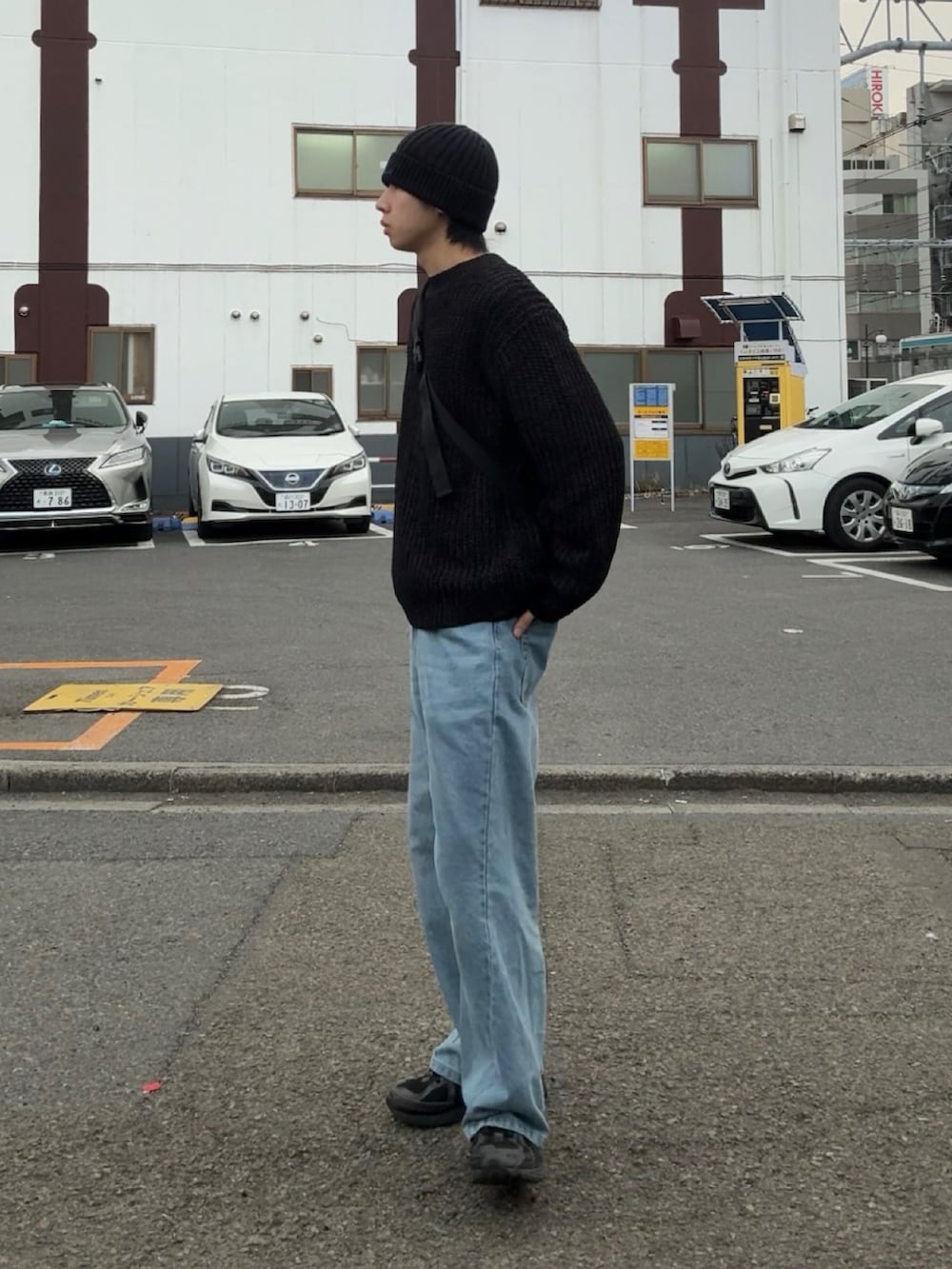 ブラック系のニット/セーター、ブルー系のデニムパンツ、ブラック系のスニーカーを着用したメンズの春コーディネートの2枚目の写真