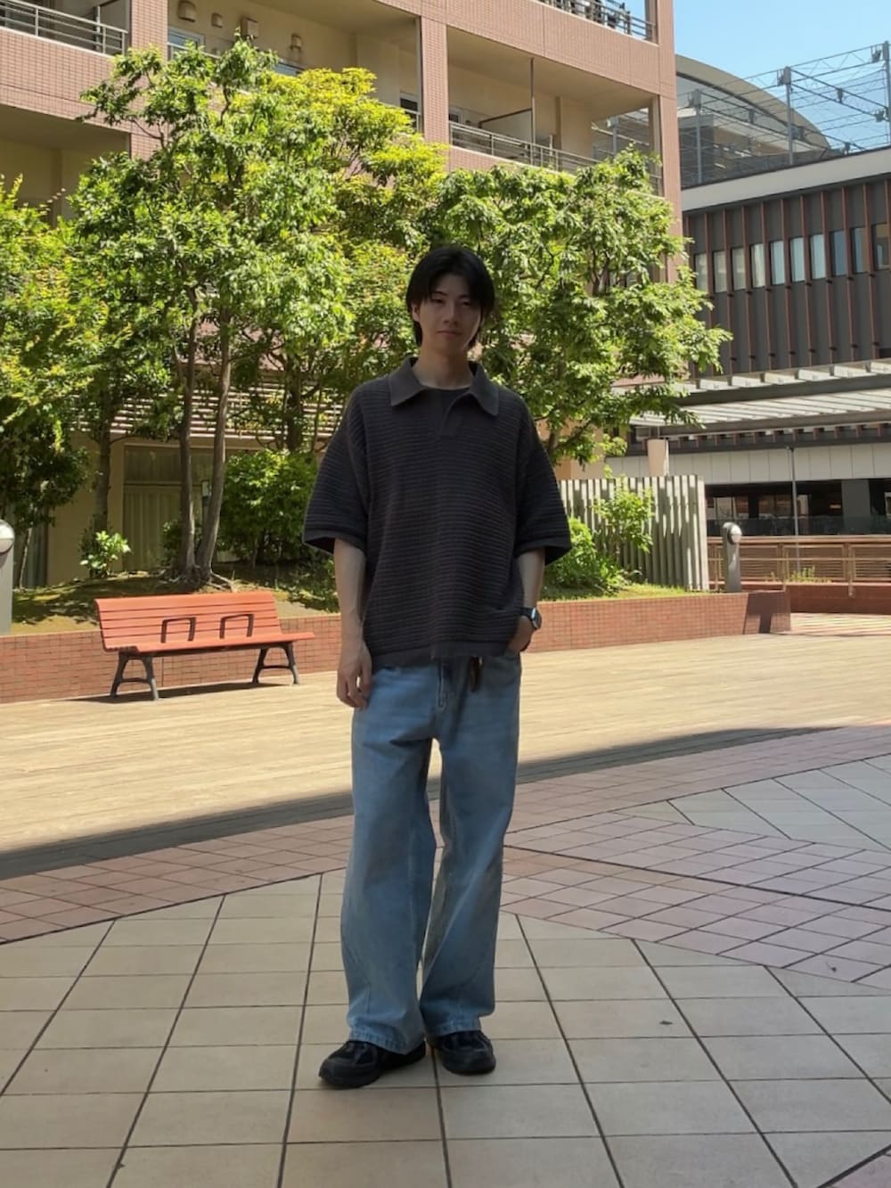 グレー系のポロシャツ、ブルー系のデニムパンツ、ブラック系のスニーカーを着用したメンズの春コーディネートの2枚目の写真