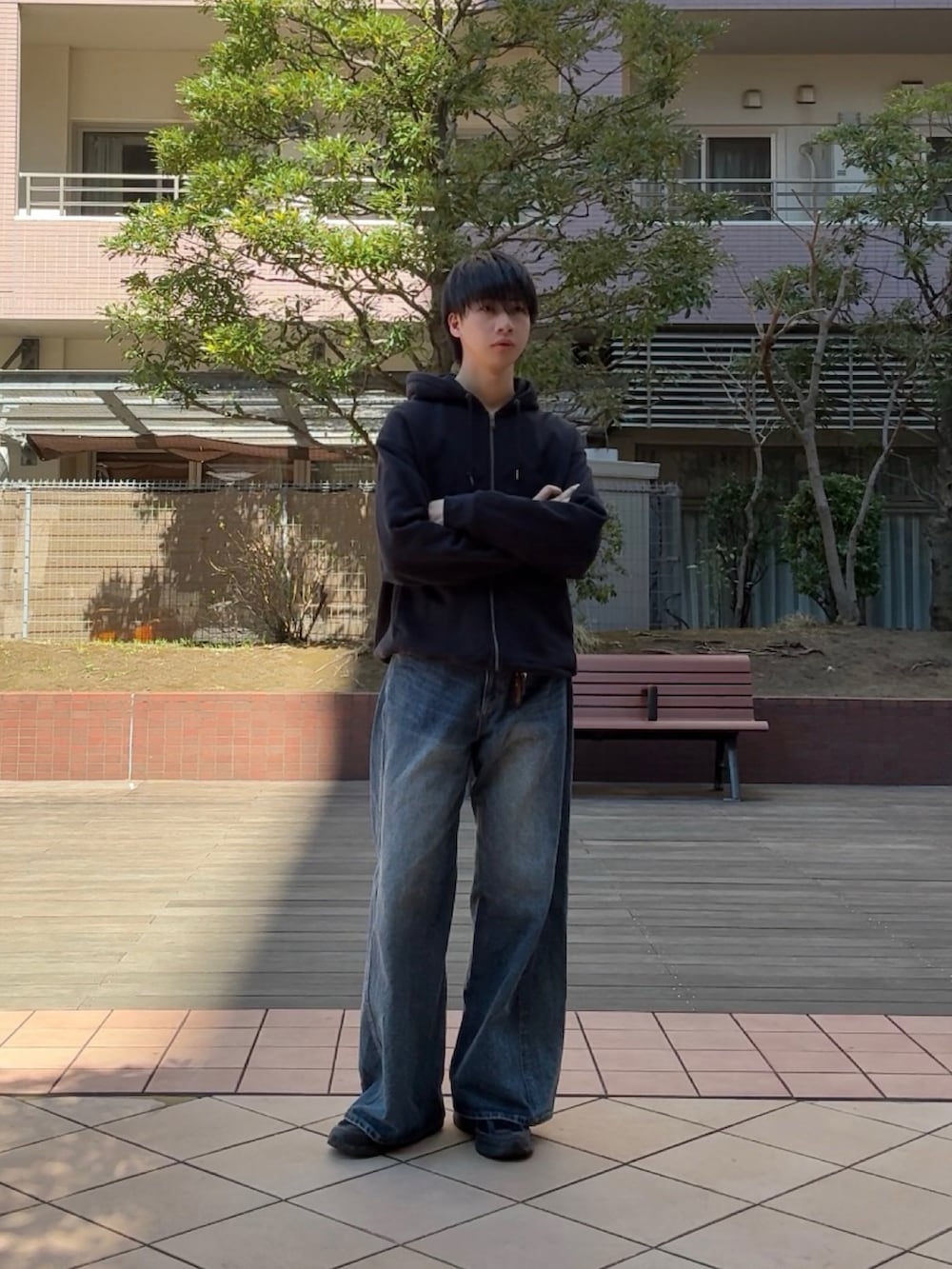 ブルー系のデニムパンツ、ブラック系のスニーカー、ブラック系のパーカーを着用したメンズの春コーディネートの3枚目の写真