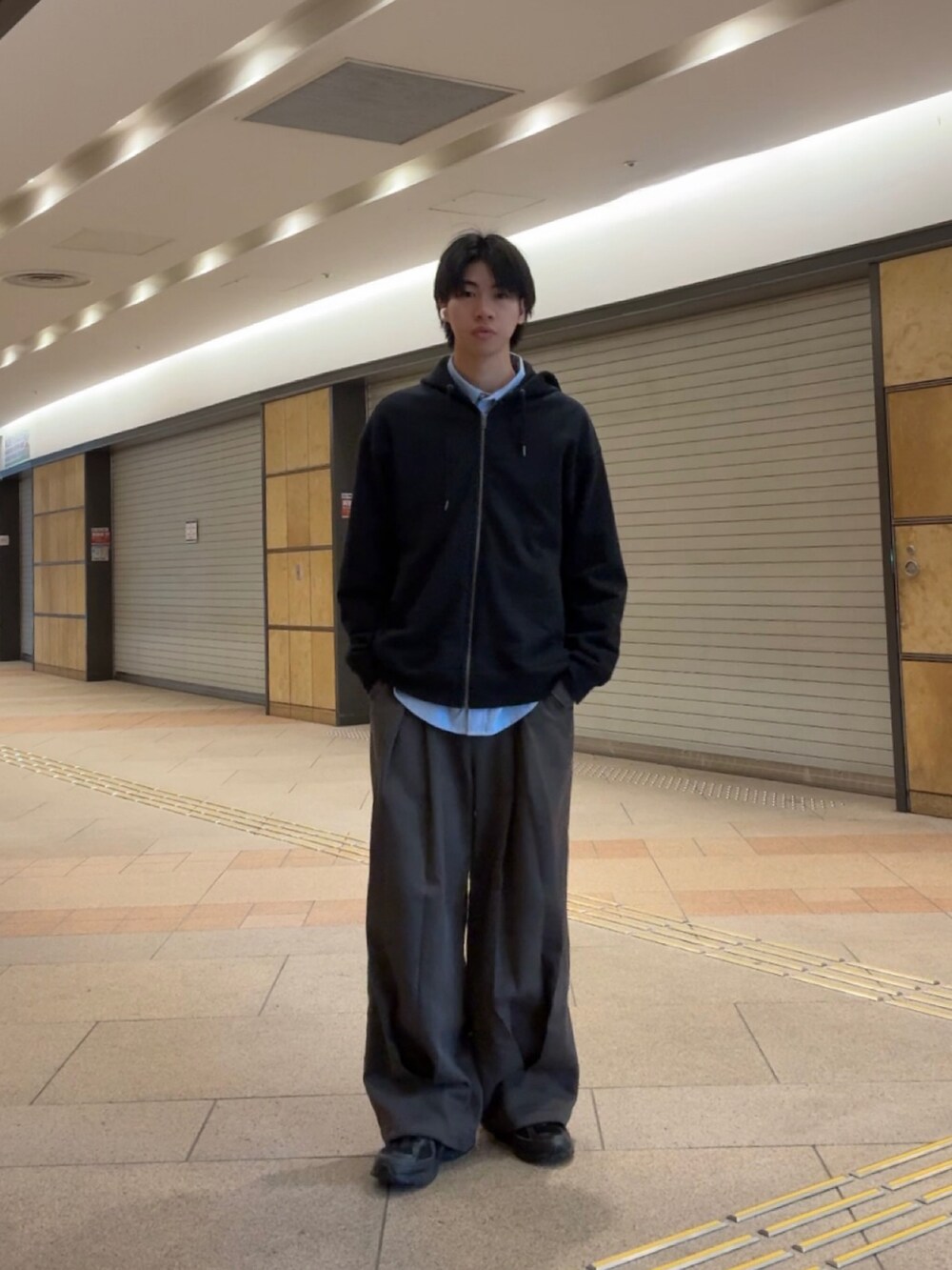 ブラック系のパーカー、ブルー系のシャツ/ブラウス、グレー系のスラックスを着用したメンズの春コーディネートの2枚目の写真