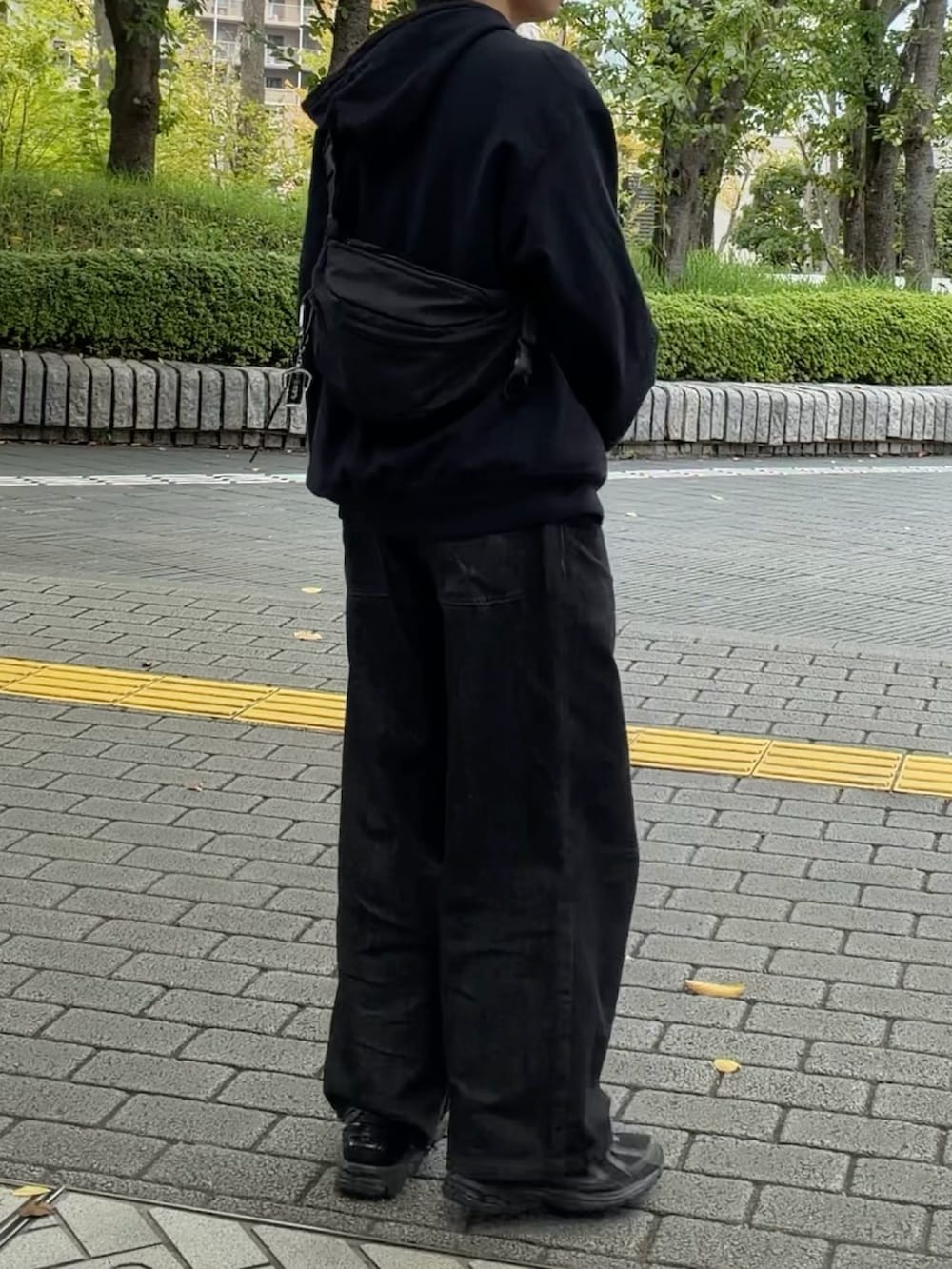 ブラック系のパーカー、ブラック系のボディバッグ/ウエストポーチ、ブラック系のデニムパンツを着用したメンズの秋コーディネートの2枚目の写真