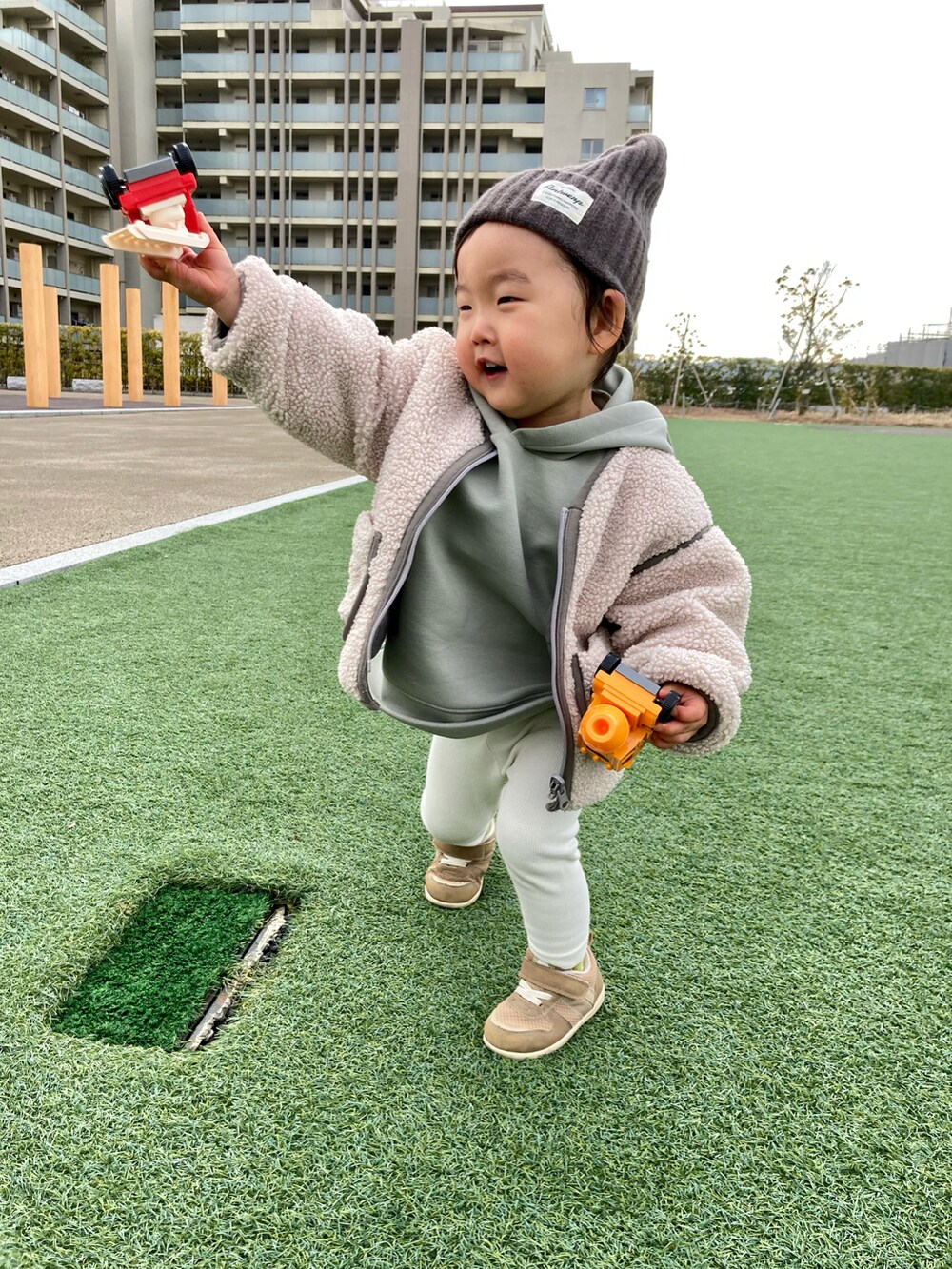 グリーン系のパーカー、ホワイト系のブルゾン、ベージュ系のスニーカーを着用したキッズの冬コーディネートの2枚目の写真
