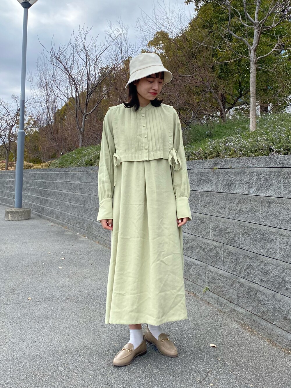 グリーン系のワンピース、ベージュ系のその他シューズ、ホワイト系のハットを着用したレディースの冬コーディネートの2枚目の写真