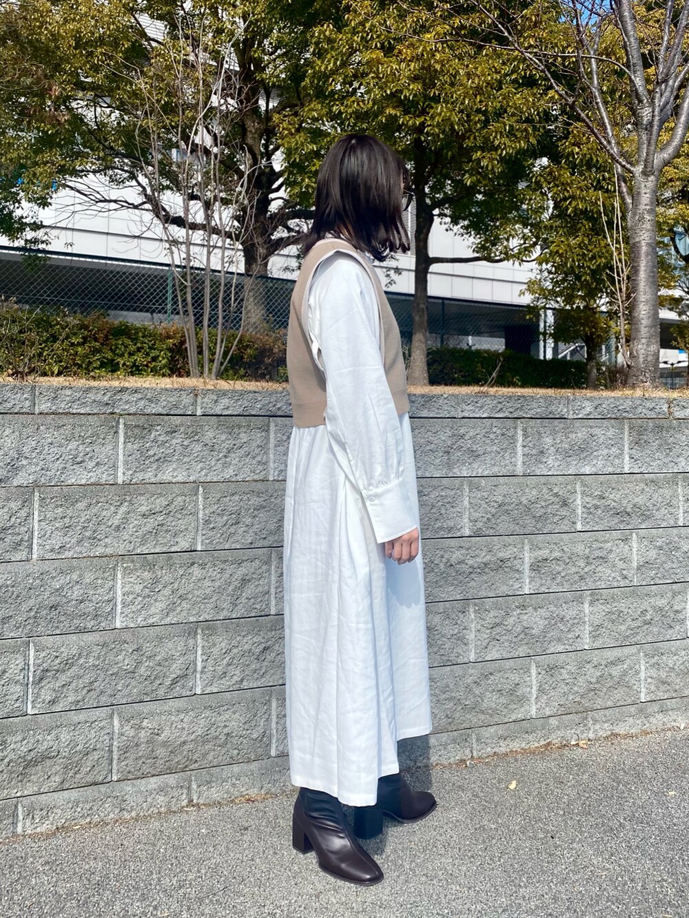 ホワイト系のワンピース、ベージュ系のベスト、ブラウン系のブーツを着用したレディースの冬コーディネートの2枚目の写真