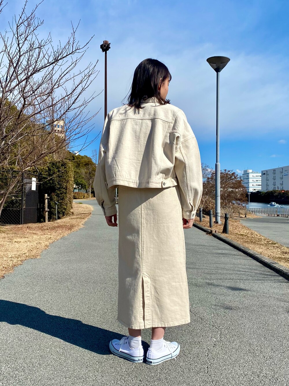 ホワイト系のデニムジャケット、ホワイト系のジャンパースカート、ホワイト系のスニーカーを着用したレディースの冬コーディネートの4枚目の写真