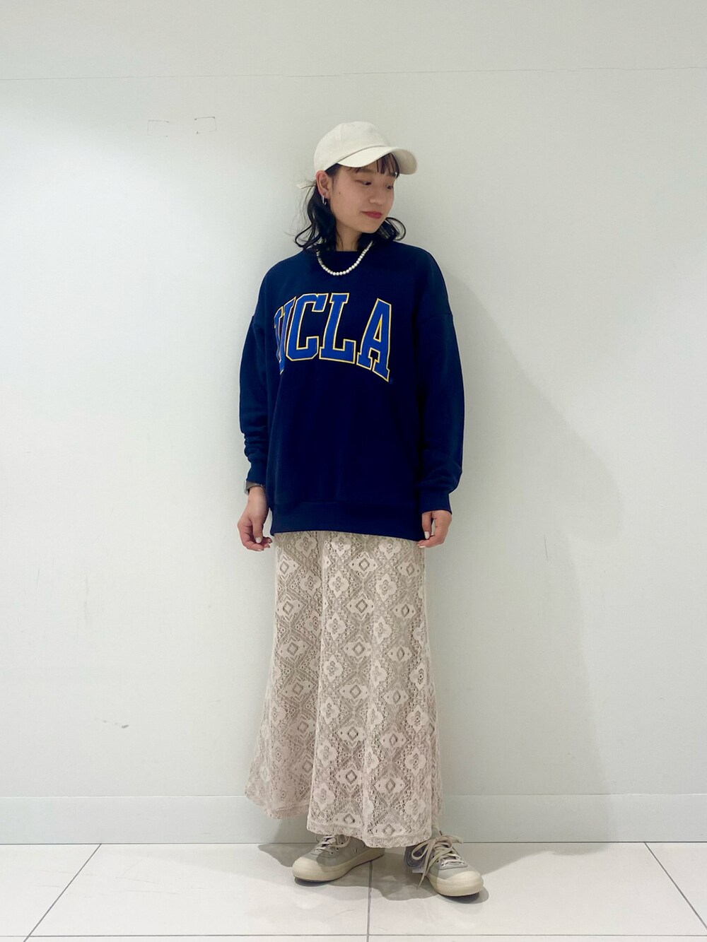 ブルー系のスウェット、ホワイト系のスカート、ホワイト系のキャップを着用したレディースの冬コーディネートの2枚目の写真