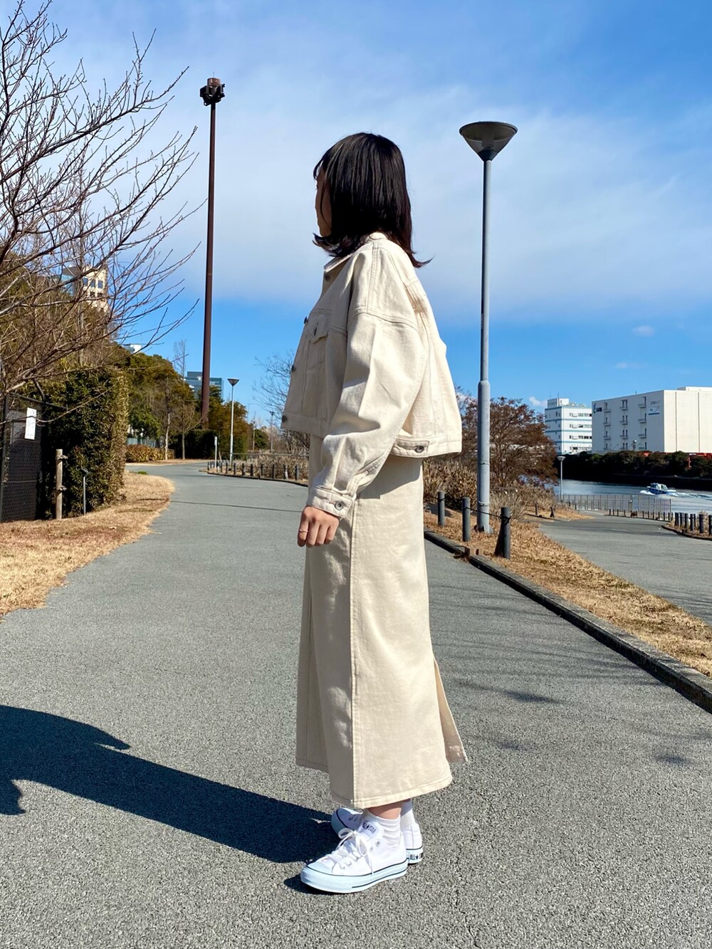 ホワイト系のデニムジャケット、ホワイト系のジャンパースカート、ホワイト系のスニーカーを着用したレディースの冬コーディネートの3枚目の写真