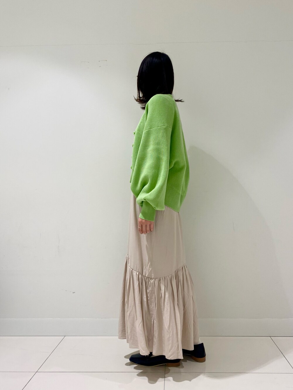 グリーン系のカーディガン/ボレロ、ホワイト系のニット/セーター、ブラック系のローファーを着用したレディースの冬コーディネートの2枚目の写真