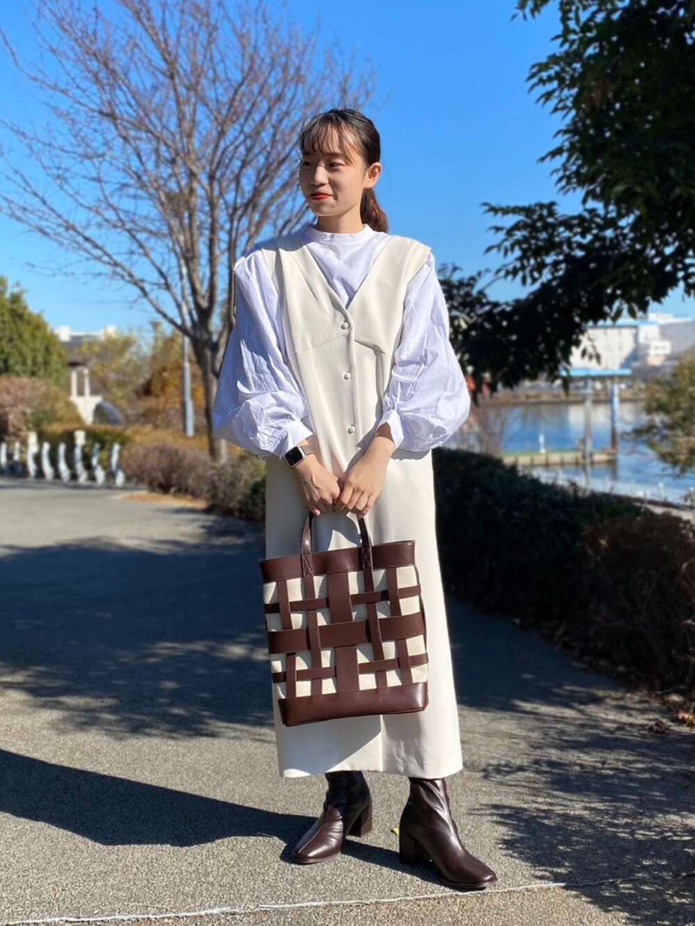 ホワイト系のジャンパースカート、ブラウン系のブーツ、ホワイト系のシャツ/ブラウスを着用したレディースの冬コーディネートの2枚目の写真