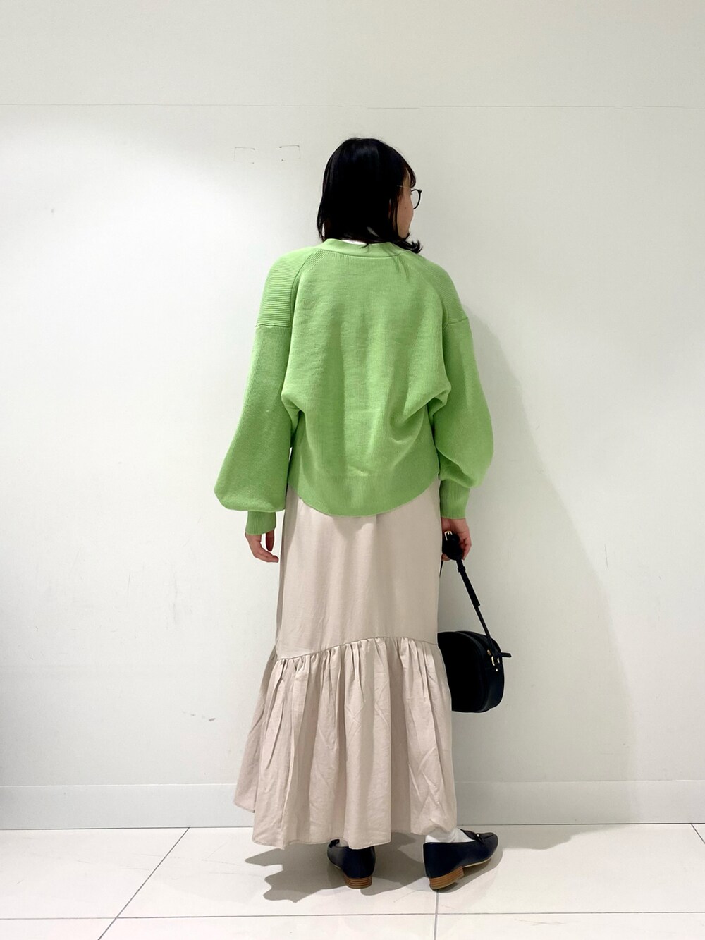 グリーン系のカーディガン/ボレロ、ホワイト系のニット/セーター、ブラック系のローファーを着用したレディースの冬コーディネートの3枚目の写真